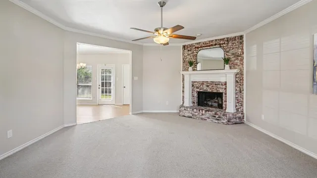 a view of an empty room with chandelier and fireplace