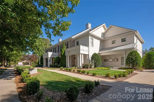 a view of a white house next to a yard with big trees