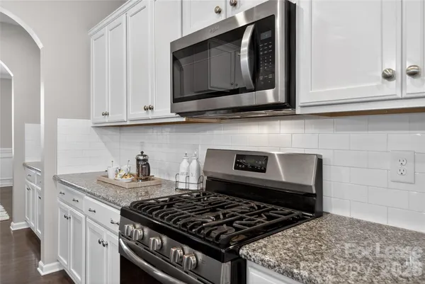 a kitchen with stainless steel appliances granite countertop white cabinets and a stove top oven