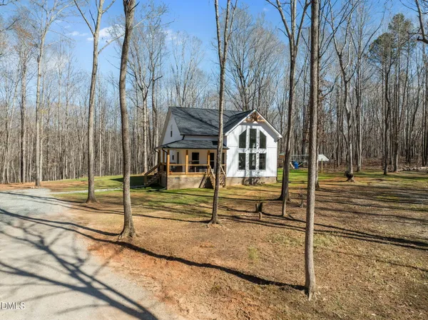 a view of a house with a yard and large trees