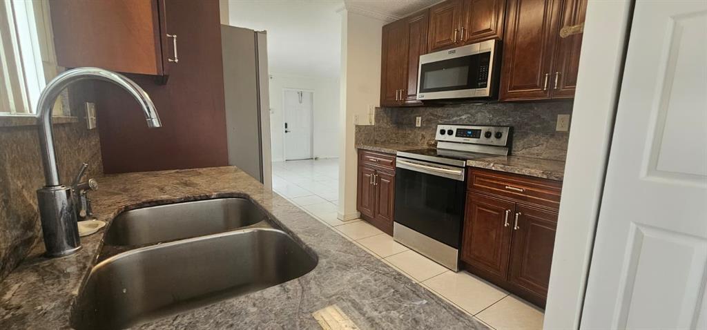 5580 Plunkett Street Hollywood, FL 33021 - Photo 2 of 13 a kitchen with stainless steel appliances granite countertop a refrigerator a stove top oven and sink