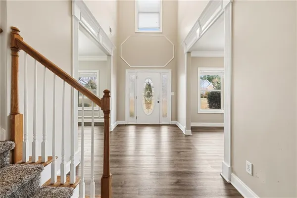 an empty room with wooden floor chandelier fan and windows