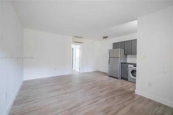 a view of a kitchen with a refrigerator and a wooden floor