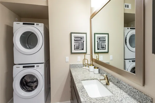 a bathroom with a granite countertop a sink and a washer dryer