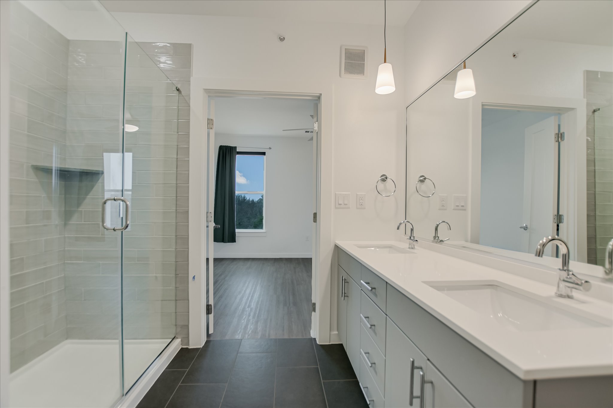 4801 Springdale Road, Unit 1207 Austin, TX 78723 - Photo 6 of 10 Full bathroom with a shower stall, double vanity, and dark tile patterned flooring