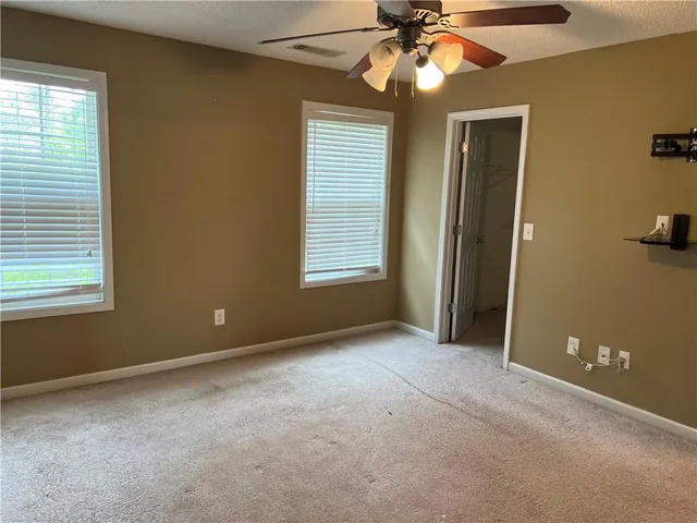 an empty room with windows and fan