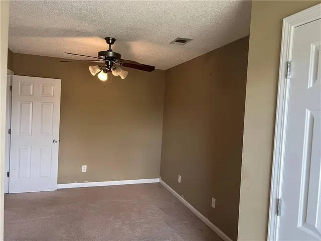 an empty room with a chandelier fan and windows
