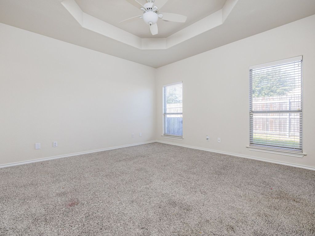 2209 Lark Lane Taylor, TX 76574 - Photo 16 of 25 an empty room with a chandelier fan and windows
