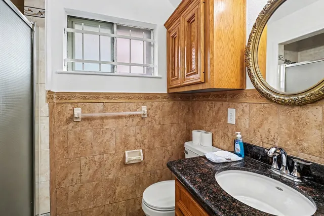 a bathroom with a granite countertop toilet sink and mirror