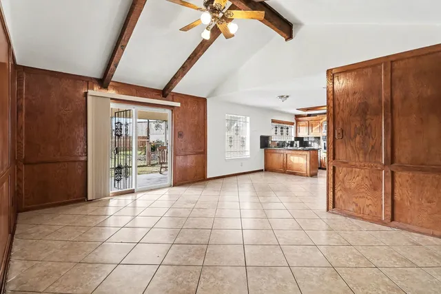 a view of a refrigerator in kitchen and an empty room with windows