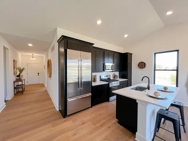 a kitchen with a stove a sink and a living room