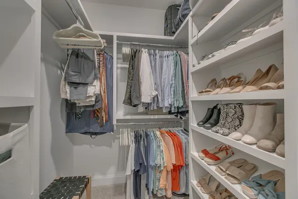 a view of walk in closet with clothes and shoes