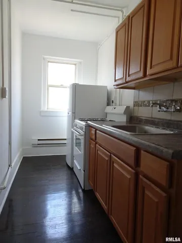 a kitchen with kitchen island granite countertop a sink cabinets and wooden floor
