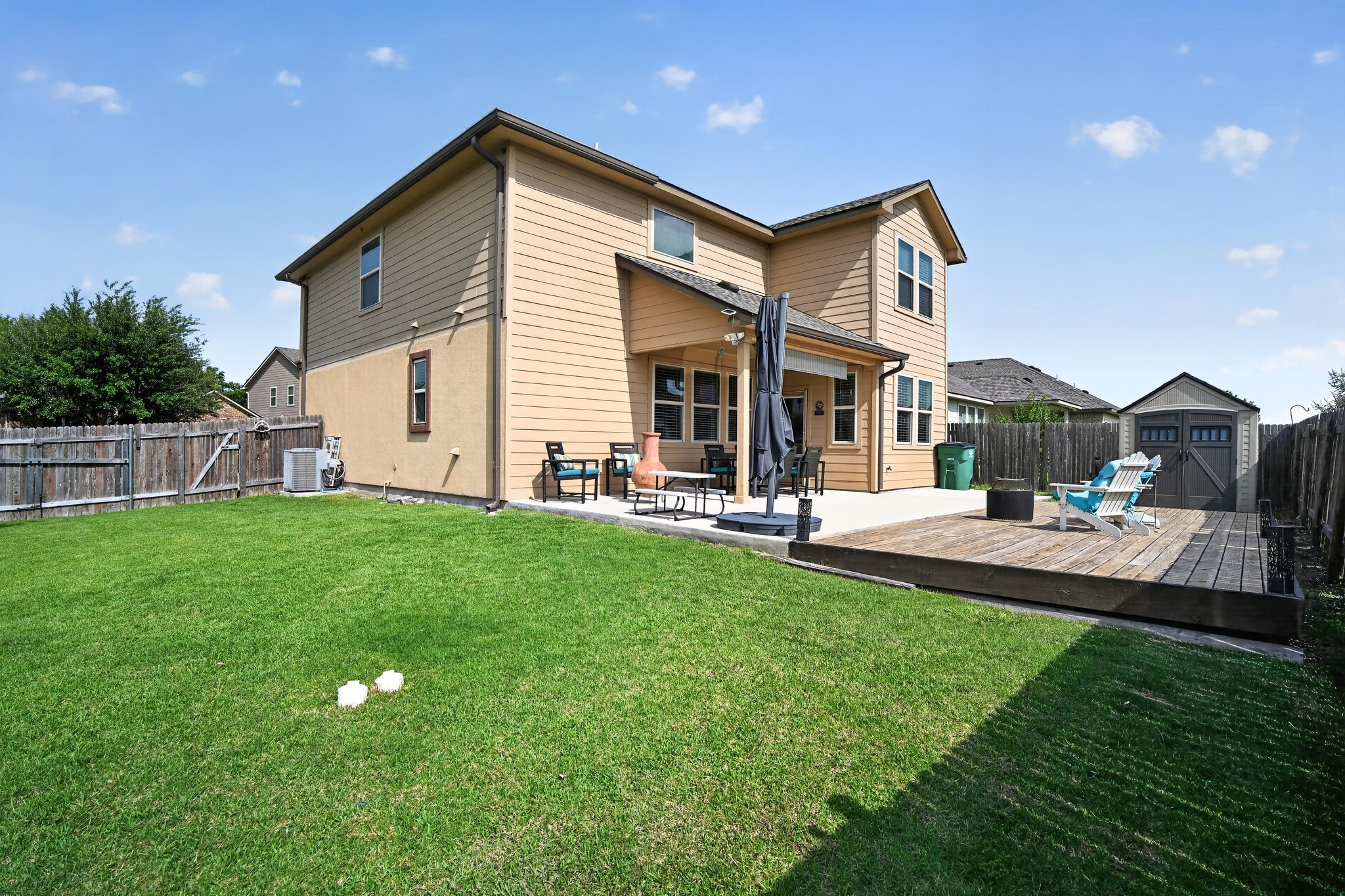 16816 Ruggio Road Pflugerville, TX 78660 - Photo 1 of 30 A spacious backyard features a concrete patio, wooden deck, and mature privacy fencing.