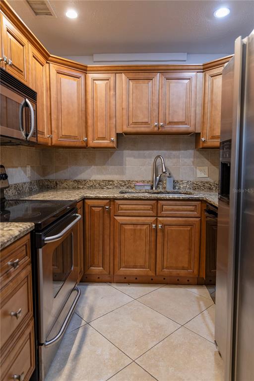 4805 Rilma Avenue, Unit 106 Sarasota, FL 34234 - Photo 20 of 24 a kitchen with stainless steel appliances granite countertop a stove a sink and a microwave