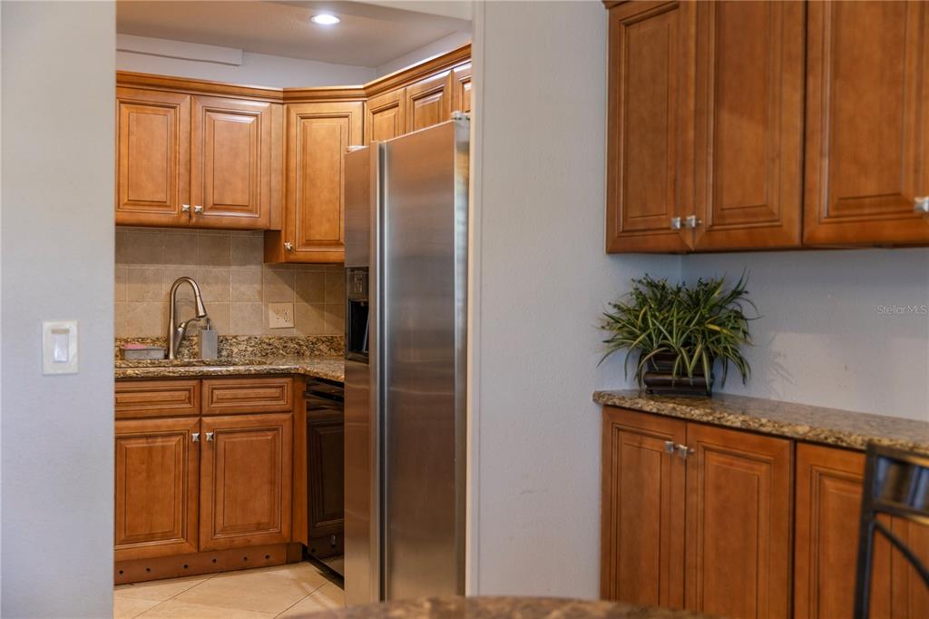 4805 Rilma Avenue, Unit 106 Sarasota, FL 34234 - Photo 6 of 24 a kitchen with stainless steel appliances granite countertop a refrigerator a stove and white cabinets with wooden floor