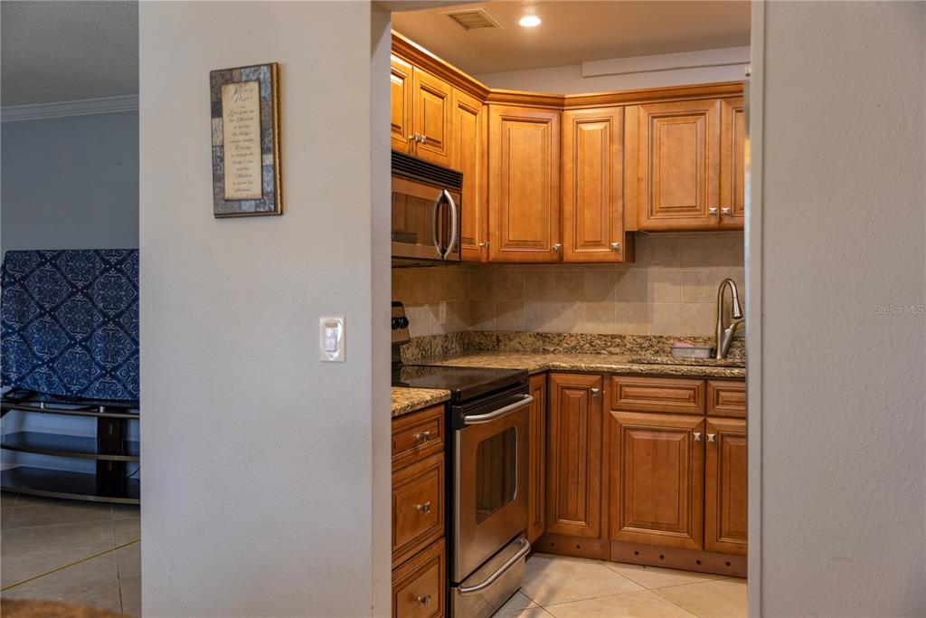 4805 Rilma Avenue, Unit 106 Sarasota, FL 34234 - Photo 7 of 24 a kitchen with stainless steel appliances granite countertop a stove a sink and a refrigerator