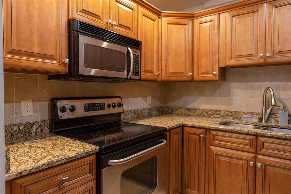 4805 Rilma Avenue, Unit 106 Sarasota, FL 34234 - Photo 8 of 24 a kitchen with granite countertop a stove top oven microwave and cabinets