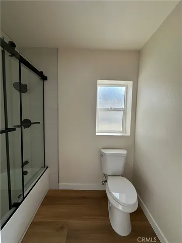 an empty room with wooden floor ceiling fan and windows