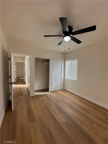 a view of empty room with wooden floor and ceiling fan