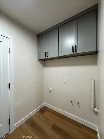 a view of a refrigerator in kitchen and an empty room with wooden floor