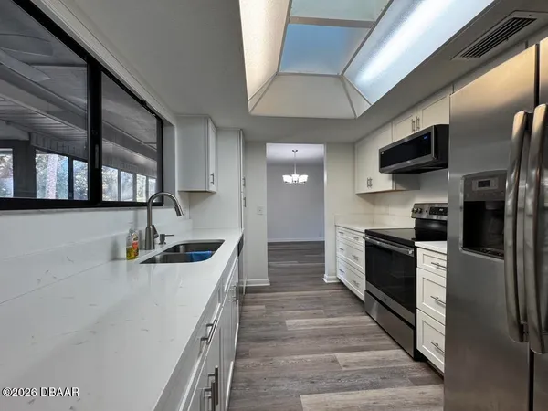 a kitchen with stainless steel appliances granite countertop a refrigerator a stove and a sink with wooden floor