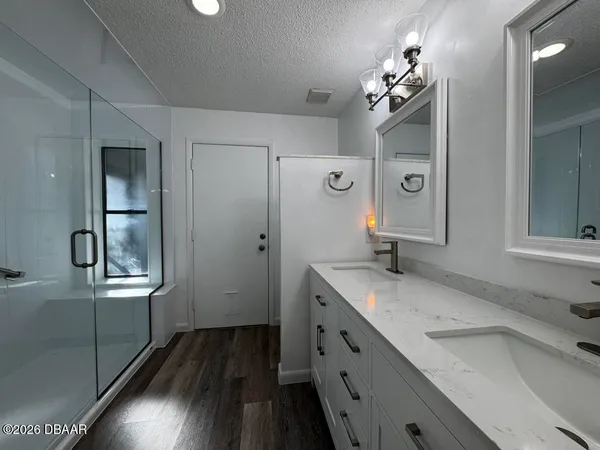 a spacious bathroom with a granite countertop sink a mirror and shower