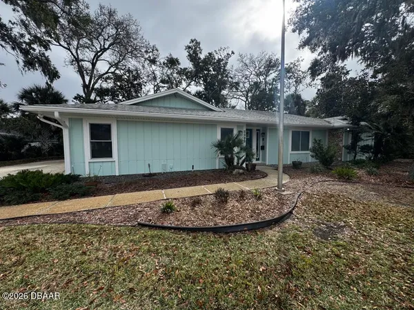a front view of house with yard and trees around