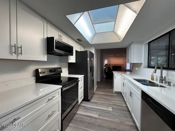a large kitchen with stainless steel appliances granite countertop a stove a sink and a microwave