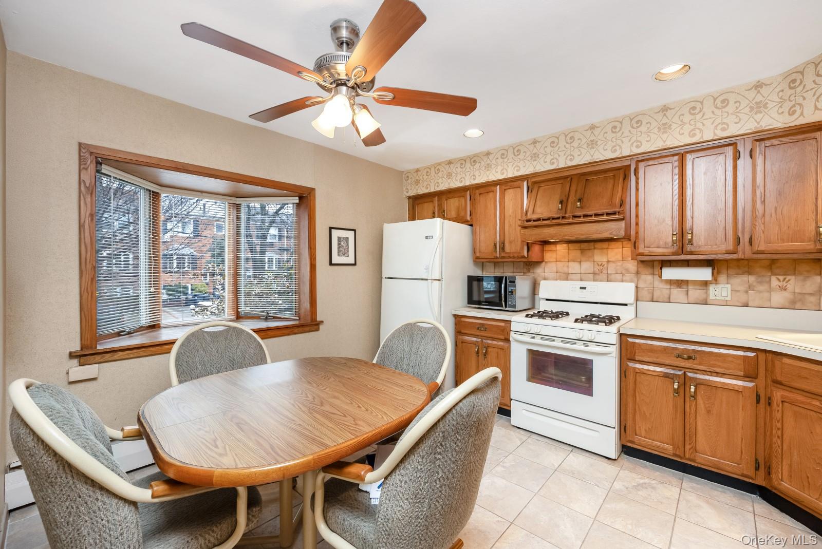 69-31 61st Road Queens, NY 11379 - Photo 2 of 28 a kitchen with stainless steel appliances granite countertop a stove a refrigerator a sink dishwasher a dining table and chairs with wooden floor