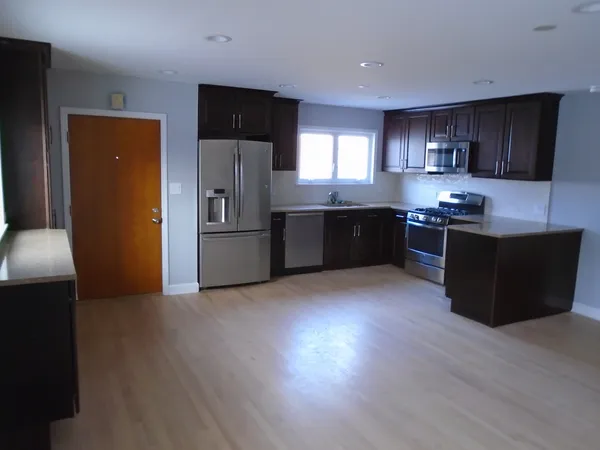 a kitchen with stainless steel appliances granite countertop a refrigerator a stove top oven a sink with wooden floors and cabinets