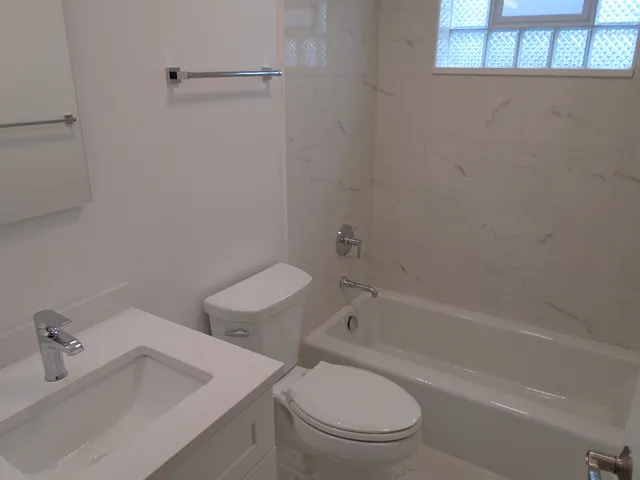 a white toilet and tub sitting next to a bathroom sink