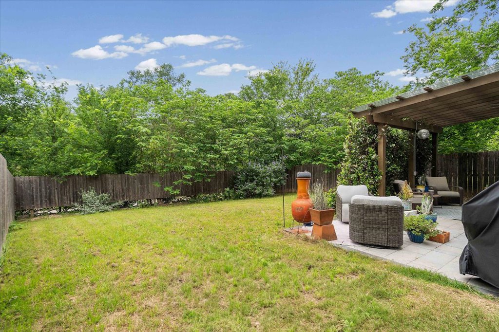 1800 Webberville Road, Unit B Austin, TX 78721 - Photo 30 of 30 Expansive backyard featuring a lush lawn, mature perimeter trees, a wooden privacy fence, a paved patio, and an overhead pergola structure