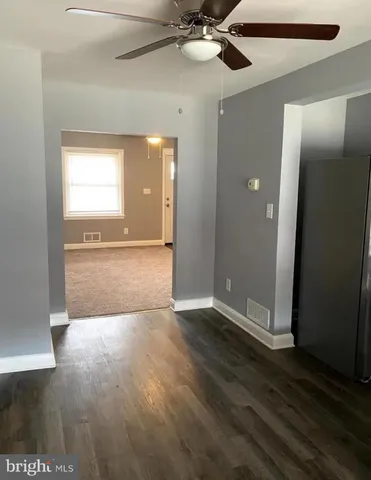 an empty room with wooden floor cabinet and windows