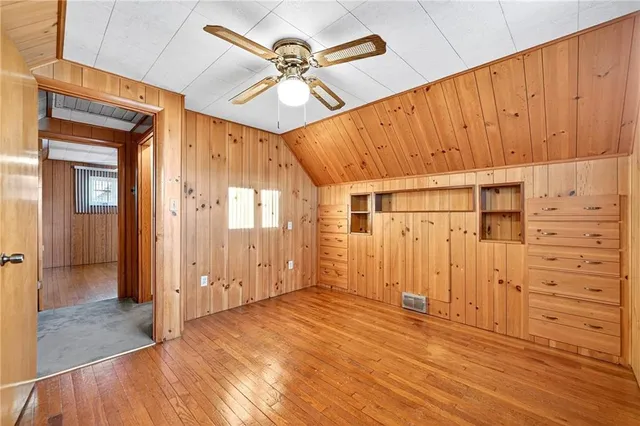 an empty room with wooden floor closet and windows
