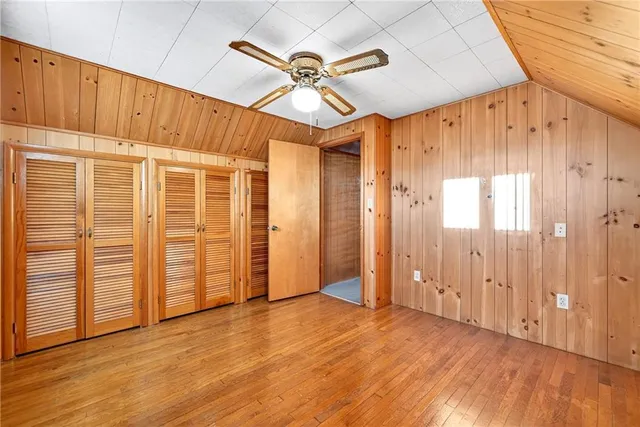 an empty room with wooden floor staircase and windows