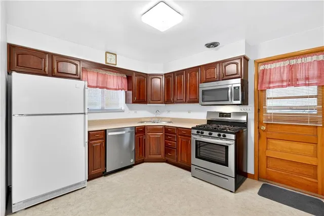 a kitchen with stainless steel appliances granite countertop a refrigerator a stove a sink and a microwave