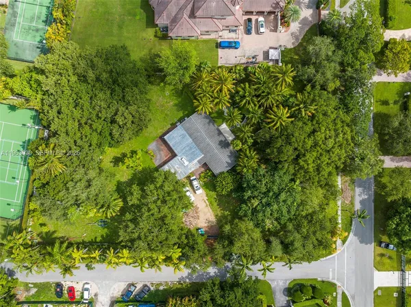 an aerial view of a house with a yard and trees all around