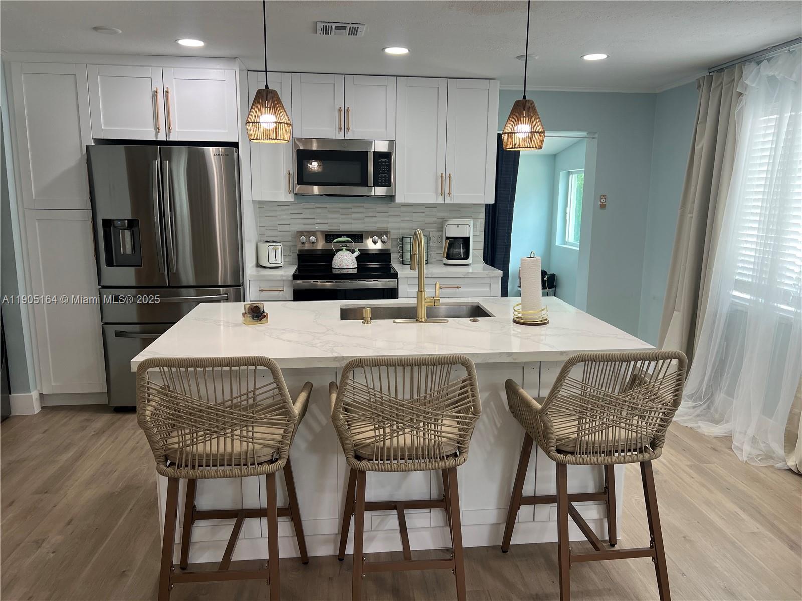 59 Tarpon Avenue Key Largo, FL 33037 - Photo 5 of 16 a kitchen with stainless steel appliances a dining table chairs refrigerator and microwave