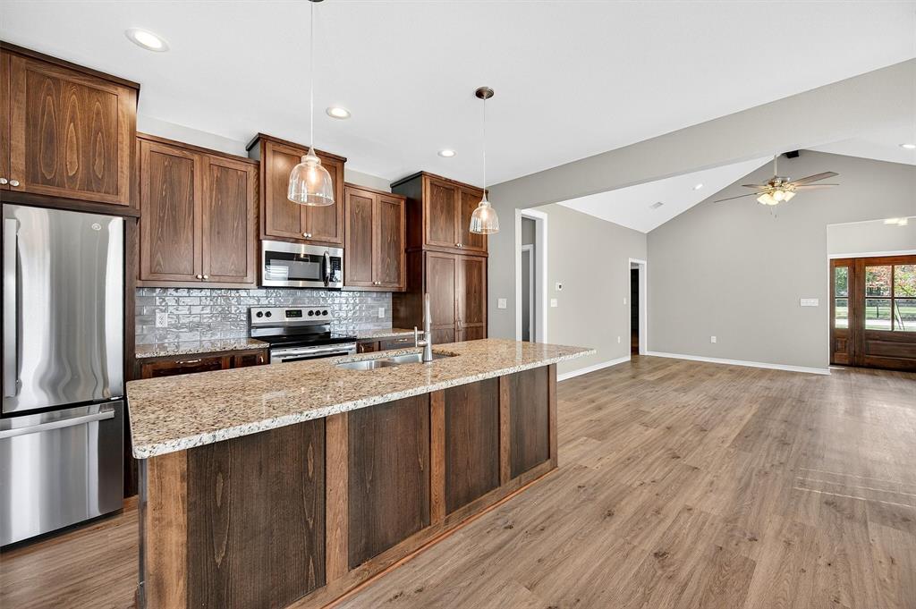 508 Goodjohn Street Collinsville, TX 76233 - Photo 12 of 40 Kitchen featuring stainless steel appliances, decorative light fixtures, light stone counters, lofted ceiling, and decorative backsplash