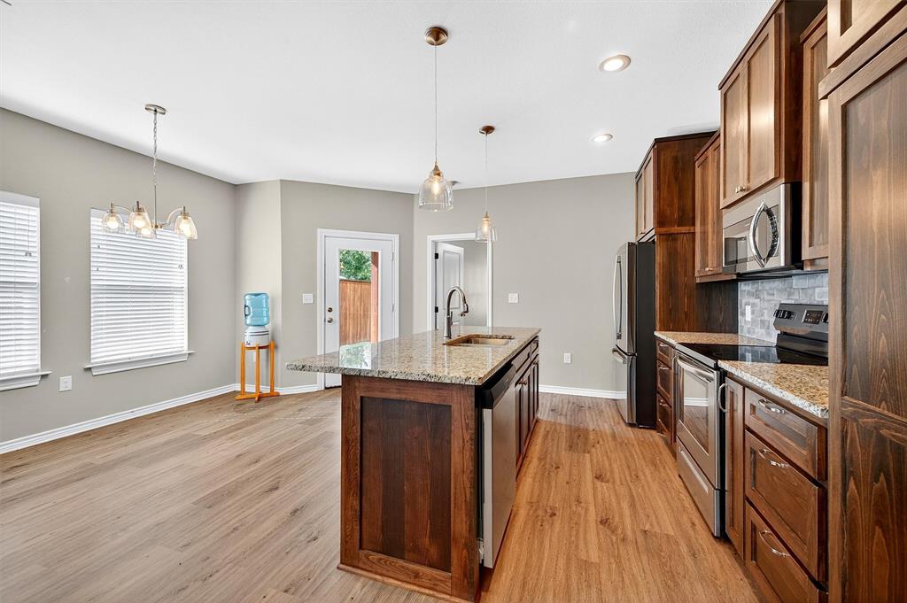 508 Goodjohn Street Collinsville, TX 76233 - Photo 16 of 40 Kitchen featuring stainless steel appliances, light stone countertops, hanging light fixtures, a center island with sink, and recessed lighting