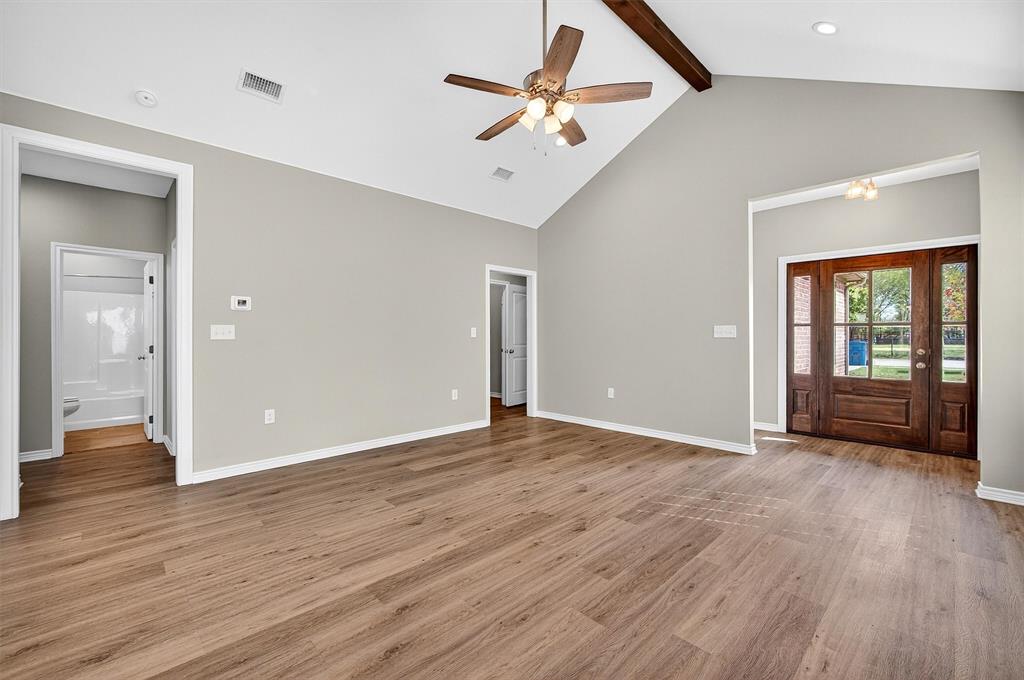 508 Goodjohn Street Collinsville, TX 76233 - Photo 5 of 40 Unfurnished living room featuring high vaulted ceiling, light wood-type flooring, beamed ceiling, and a ceiling fan