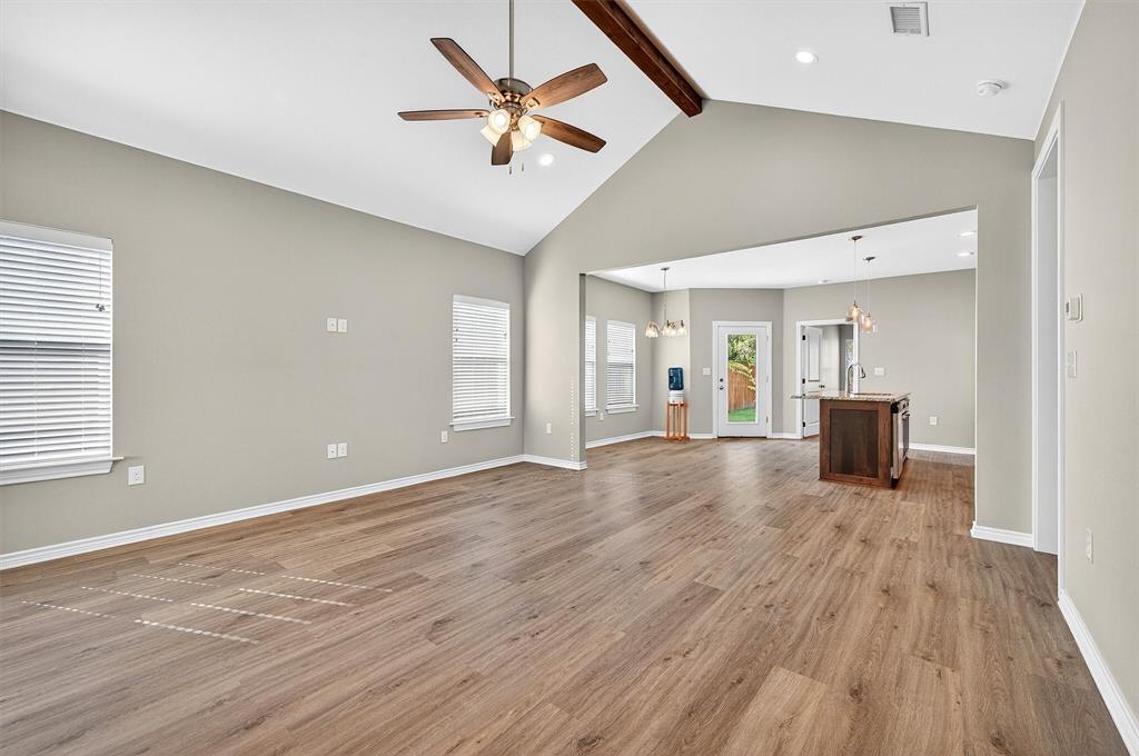508 Goodjohn Street Collinsville, TX 76233 - Photo 7 of 40 Unfurnished living room with beamed ceiling, high vaulted ceiling, a chandelier, light wood finished floors, and a ceiling fan