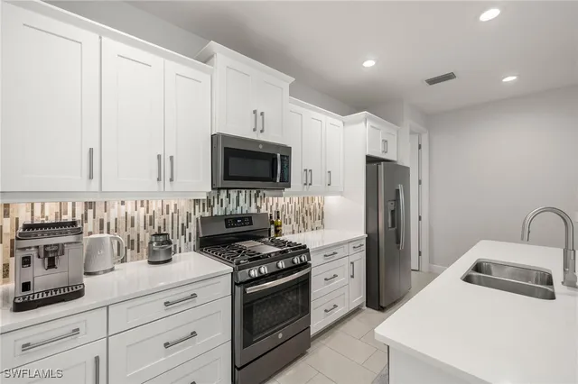 a kitchen with refrigerator a microwave a sink and cabinets