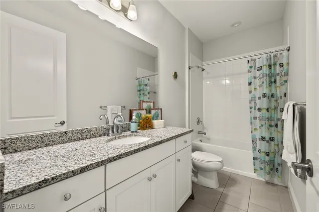 a bathroom with a granite countertop sink a toilet a mirror and shower