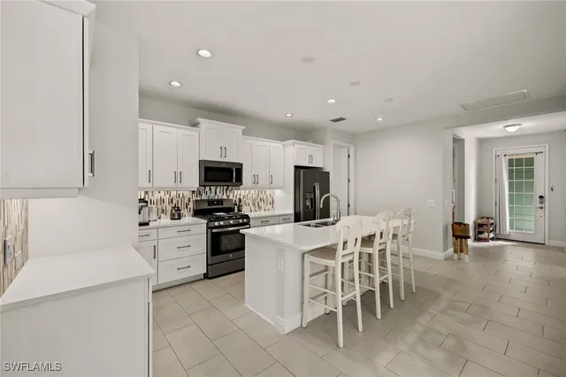 a kitchen with stainless steel appliances kitchen island granite countertop a sink a stove a dining table and chairs