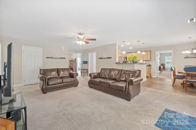 a living room with furniture and a dining table with kitchen view