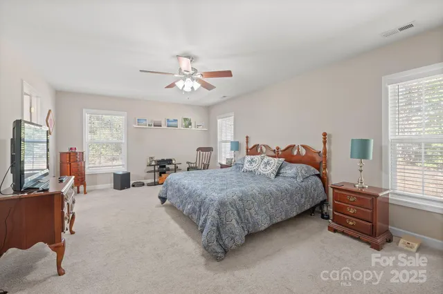 a spacious bedroom with a bed a chandelier and a large window