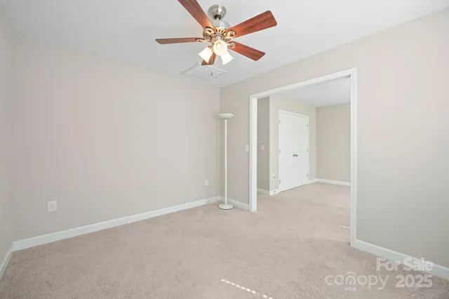 an empty room with closet and a ceiling fan