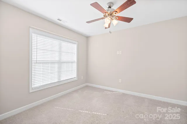 an empty room with a window and a fan